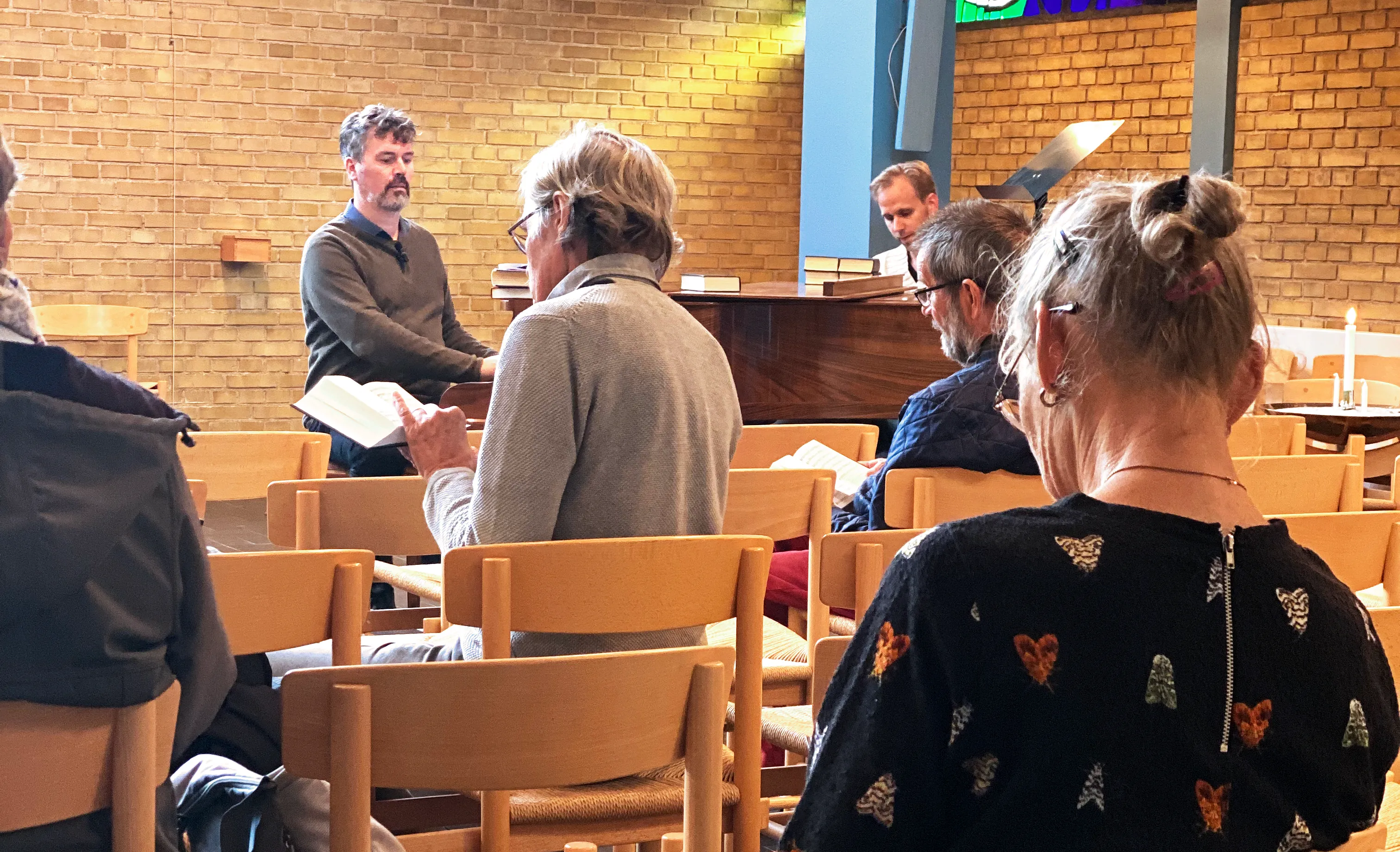 En taler taler til et siddende publikum ved et socialt kirkearrangement.